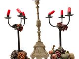 two candeliers with red candles and fruit on them