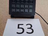un clavier noir posé sur une table, à côté d'un panneau blanc
