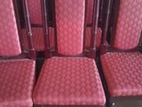 six chairs with red upholstered seats are lined up in a row