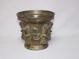 un vase en argent orné d'un visage, posé sur une table
