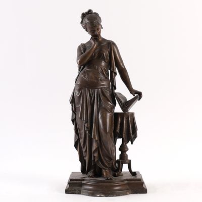 an antique bronze statue of a woman holding a watering pot