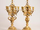 pair of antique brass candelabs on pedestals on a white background