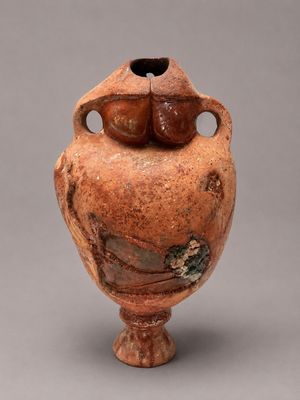un vase marron orné d'un oiseau sur un fond gris