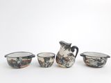three small bowls and a pitcher sitting next to each other on a white surface