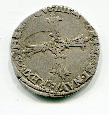 une vieille pièce d'argent ornée d'une croix, posée sur une surface blanche