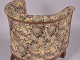 an upholstered chair with a floral upholstered back and wooden legs