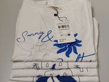 trois t-shirts blancs ornés de motifs bleus et blancs sont empilés les uns sur les autres
