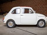 a small white car parked in front of a brick wall