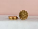 a gold coin sitting on top of a white counter next to a pink wall
