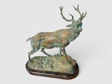 sculpture en bronze représentant un cerf, posée sur un socle en bois, sur fond blanc