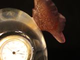 someone is holding a glass clock with a snail on top of it