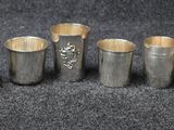 six vases en argent sont alignés sur une surface noire