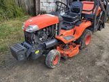 un petit tracteur orange garé devant une grange