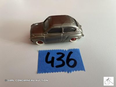 une petite voiture en argent posée sur une feuille de papier bleue