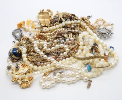 un tas de perles et d'autres bijoux posés sur une surface blanche