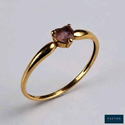gros plan d'une bague en or avec une pierre rose