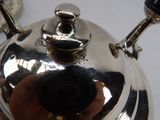 a silver tea pot sitting on a table next to a tea kettle