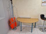 une petite table sur laquelle est posé un ordinateur portable, dans un coin de la pièce