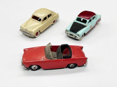 trois petites voitures assises l'une à côté de l'autre sur une surface blanche