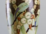 a vase with a bird on it sitting on a stand