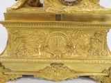 a gold clock that has a statue on top of it