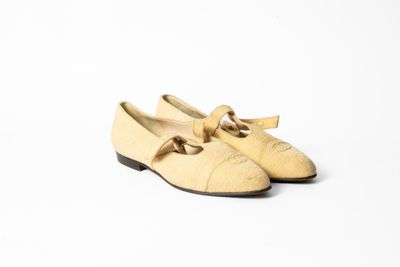 chaussures en cuir beige ornées de nœuds sur le bout, sur fond blanc