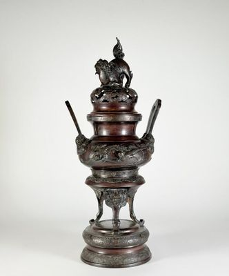 un vase antique en bronze surmonté d'un oiseau