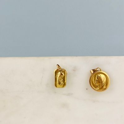 un gros plan sur une paire de boucles d'oreilles en or posées sur une surface en marbre
