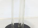 two clear glass tubes on a black stand with a black base