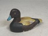 a small wooden duck sitting on a white surface