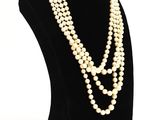 a white pearl necklace on a black mannequin