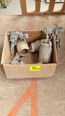 a cardboard box with two spray guns in it on the floor