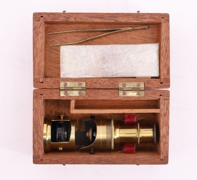 une vieille boîte en bois contenant un télescope, posée sur une surface blanche