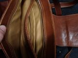 a person holding a brown leather bag with a brown handle