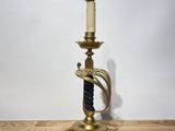 a brass plated candle holder on a wooden table with a white wall in the background