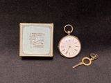 a pocket watch and a key sitting next to each other