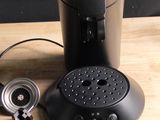 a coffee maker sitting on a wooden table with a cup of coffee