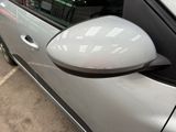 a side view mirror of a silver car in a parking lot
