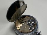 a silver pocket watch sitting on a white surface