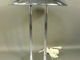 une lampe de table argentée sur laquelle est posé un papillon blanc