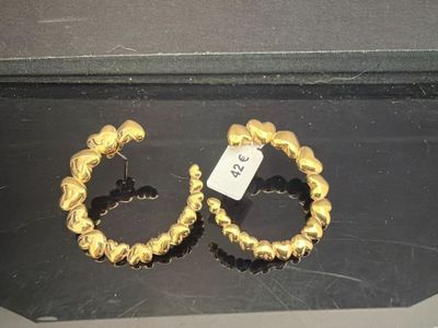 une paire de boucles d'oreilles créoles en or exposée dans une vitrine