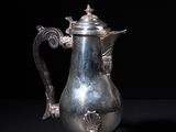 an antique silver coffee pot sitting on top of a black table