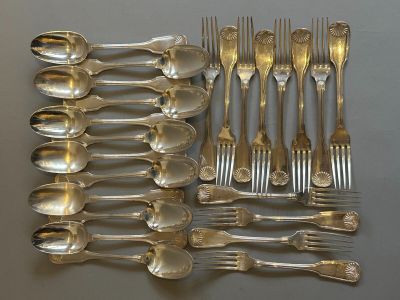 a lot of silver spoons and forks laid out on a table