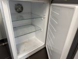 a small white refrigerator with its door open in a kitchen