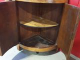 a corner cabinet that has a glass shelf in it