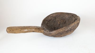 a wooden scoop with a wooden handle on a white surface