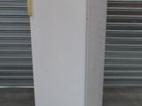 un réfrigérateur blanc avec le haut jaune, devant une porte de garage
