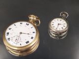 une montre de poche en or et une montre de poche en argent posées sur une table