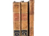 two old books sitting on top of each other on a white surface