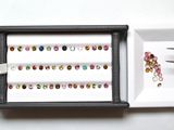 un plateau sur lequel se trouvent une paire de ciseaux, à côté d'un plateau contenant des pierres de différentes couleurs